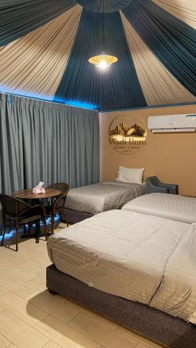 a room with two beds and a table and a tent at Wadi Rum Dome Camp in Disah