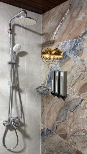 a shower in a bathroom with a stone wall at Wadi Rum Dome Camp in Disah