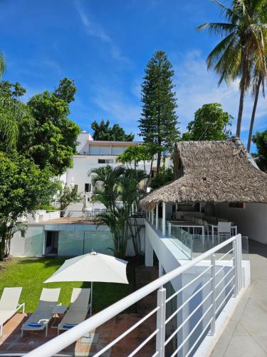 a balcony with an umbrella and chairs and a building at Luxury Villa by the Lake in Tequesquitengo
