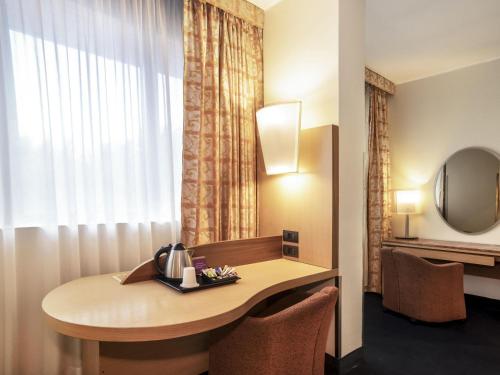 a room with a table with chairs and a window at Mercure Roma West in Mostacciano