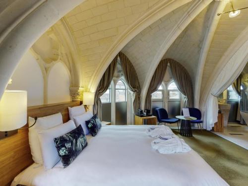 a bedroom with a large bed in a room with arches at Mercure Poitiers Centre in Poitiers