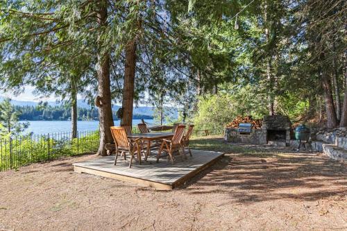 a table and chairs sitting on a wooden deck under a tree at Lakefront Cabin Dock Kayaks & Fire Pit in Hayden