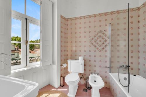 a bathroom with a toilet and a tub and a sink at Old City Guest House in Braga