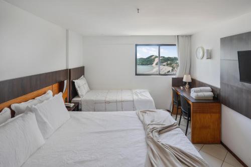 a hotel room with a bed and a desk and a television at Plaza Suíte Natal Vista Mar in Natal