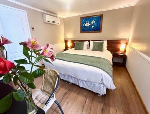 a hotel room with a bed and a vase with flowers at Hostal del Valle in Santa Cruz