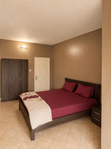 a bedroom with a large bed with red sheets at Kiki bay in Conakry