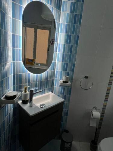 a blue tiled bathroom with a sink and a mirror at EJ&A Coastal Suites in Marsaskala