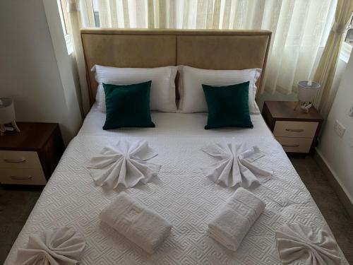 a bed with white sheets and green pillows at EJ&A Coastal Suites in Marsaskala