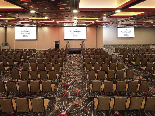 an empty room with chairs and two screens at Novotel Sydney Parramatta in Sydney