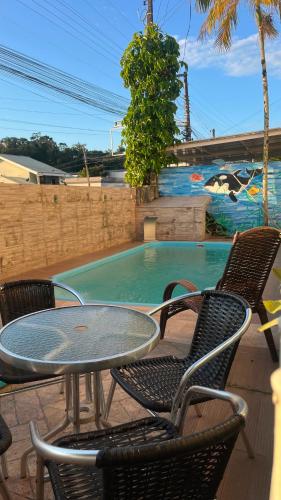 a patio with a table and chairs and a swimming pool at Pousada Ilha do Itacolomi in Penha