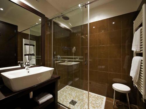 a bathroom with a sink and a glass shower at Mercure Bergamo Aeroporto in Stezzano