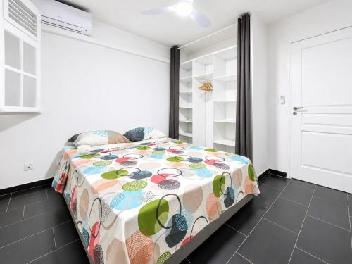 a bedroom with a bed with a colorful comforter at Villa 6 pers Jacuzzi Centre Guadeloupe in Petit-Bourg