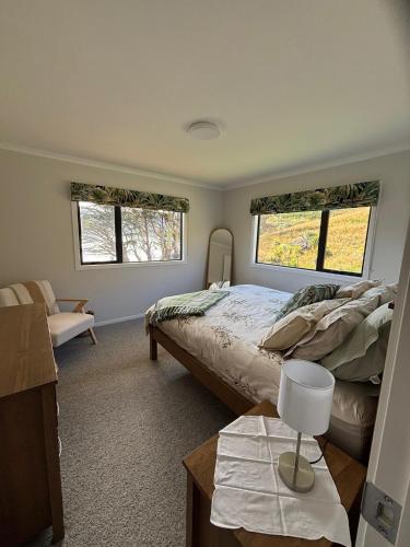 a bedroom with a large bed and two windows at Raynbird Cottage in Dunedin