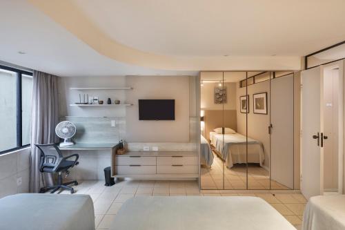a bedroom with a bed and a desk and a television at Atlântico Flat Beira Mar in Natal