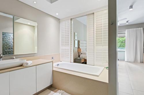 a bathroom with a tub and a sink and a mirror at Element Bay 5 in Cap Malheureux
