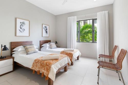 a bedroom with two beds and a chair and a window at Element Bay 5 in Cap Malheureux