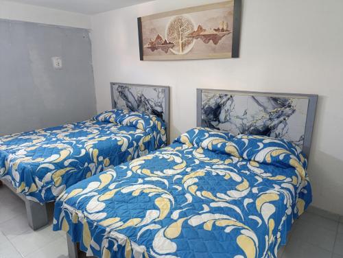 two beds with blue and yellow covers in a room at Práctico y céntrico departamento in Salamanca