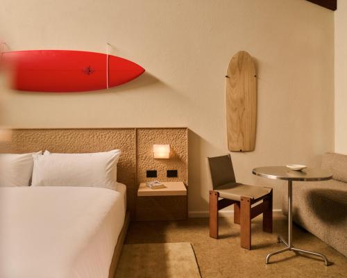 ein Hotelzimmer mit einem Bett, einem Tisch und einem roten Surfbrett in der Unterkunft Surf Hotel in Torquay