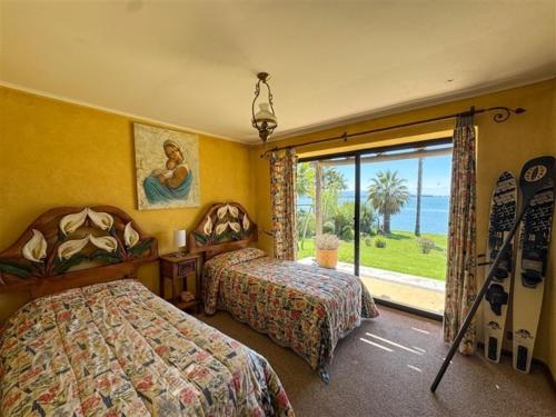 a hotel room with two beds and a window at El Estero Lago Rapel in El Estero