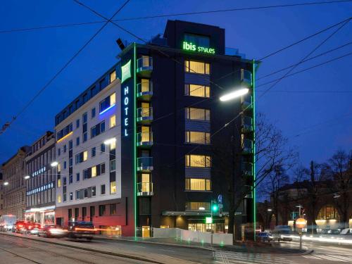 a tall building on a city street at night at Ibis Styles Wien City in Vienna