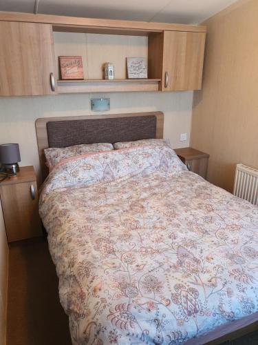 a bedroom with a large bed with a floral bedspread at 3-Bed Caravan Sleeps 8 with Enclosed Decking in Fleetwood