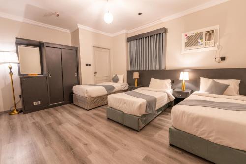 a hotel room with two beds and a tv at عالم الضيافة in Al ‘Azīzīyah