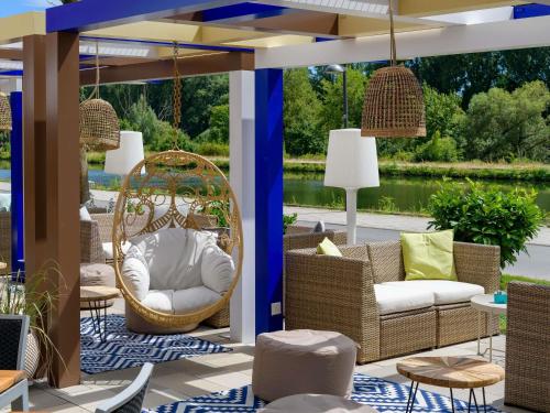 a patio with wicker chairs and a swing at Ibis Styles Regensburg in Regensburg