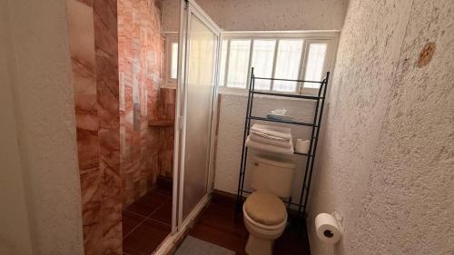 a bathroom with a toilet and a glass shower at Habitacion en residencia compartida in Mexico City