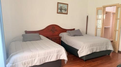 two beds in a room with white sheets at Habitacion en residencia compartida in Mexico City
