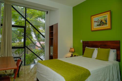 a green bedroom with a bed and a large window at Hotel Europa in Iquitos
