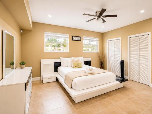 a bedroom with a white bed and a ceiling fan at 2BR with patio, grill, central AC, enclosed yard in Hollywood