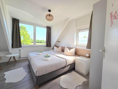 a bedroom with two beds and two windows at Villa Christina in Stevensweert