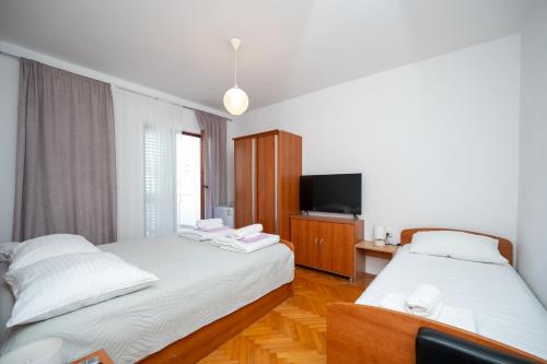 a hotel room with two beds and a television at Apartments and rooms by the sea Jakisnica, Pag - 4160 in Lun