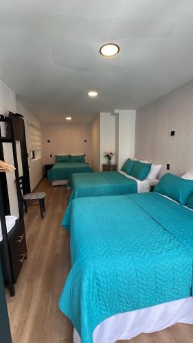 a bedroom with two beds with blue comforters at CASA LAURA hotel & suites in Cuenca