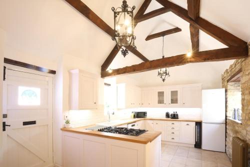 a kitchen with white cabinets and a chandelier at The Old Coach house- a delightful home from home in Witney