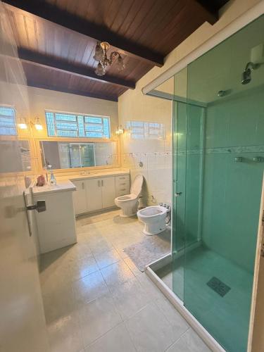 a bathroom with two toilets and a glass shower at Maresia Beach House in Rio das Ostras