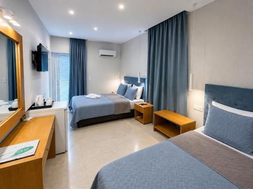 a hotel room with two beds and a desk at Castro Hotel in Amoudara Herakliou