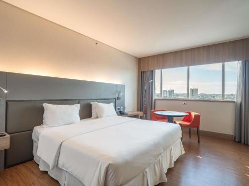 a hotel room with a large bed and a window at Mercure Uberlândia Plaza Shopping in Uberlândia