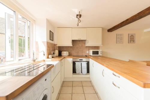 a kitchen with white cabinets and a large window at Mill View-an idyllic base to explore The Cotswolds in Northleach