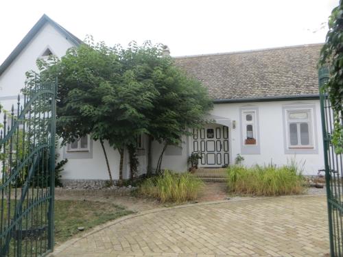 a white house with a gate and a tree at Bacchus-hof in Báta