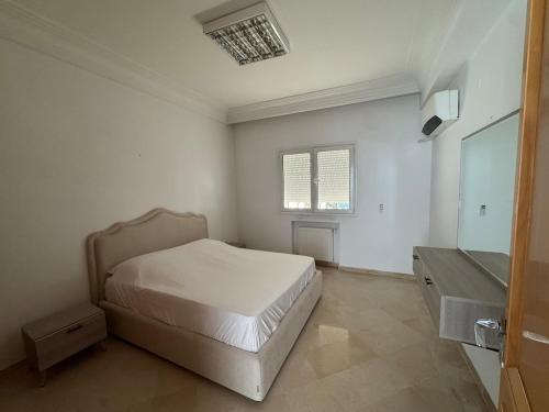 a white bedroom with a bed and a sink at Résidence Tasnim Ennasr in Ariana