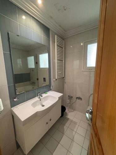a white bathroom with a sink and a mirror at Résidence Tasnim Ennasr in Ariana