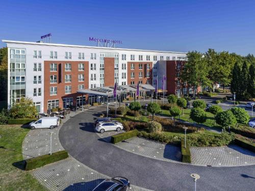 a large building with cars parked in a parking lot at Mercure Kamen Unna in Kamen
