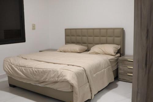 a bedroom with a large bed with a headboard and a dresser at شاليهات ذهب in Amman