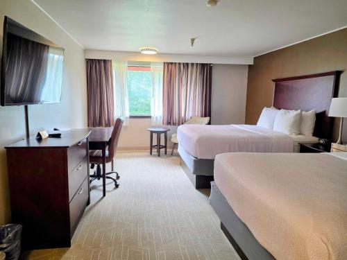 a hotel room with two beds and a desk at Ramada by Wyndham Tukwila Southcenter in Tukwila