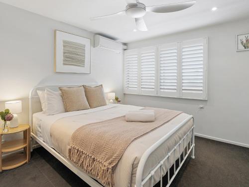 a bedroom with a large bed with white walls and windows at Wharf Lodge River View Apartment in Maroochydore