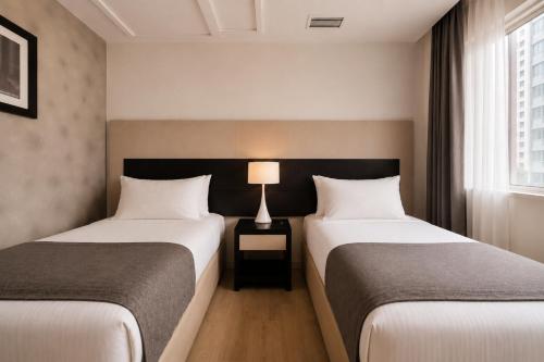 a hotel room with two beds and a lamp at Hotel Sommelier Agustinas in Santiago