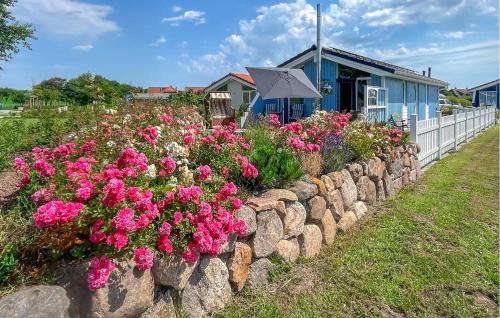 a retaining wall with pink flowers in front of a blue building at Friedrichskoog-Deichblick 4 in Friedrichskoog