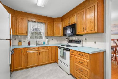 a kitchen with wooden cabinets and white appliances at Cozy Cape Escape Near Beaches Dining in Centerville
