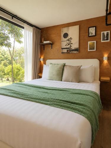 a bedroom with a large white bed with a window at How Hide Homestay in Ban Tha Makham
